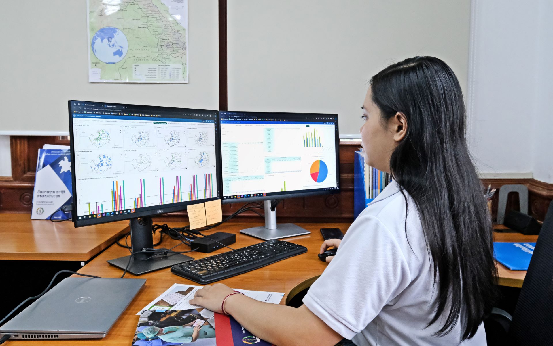 A WHO staff member works in front of two computer screens